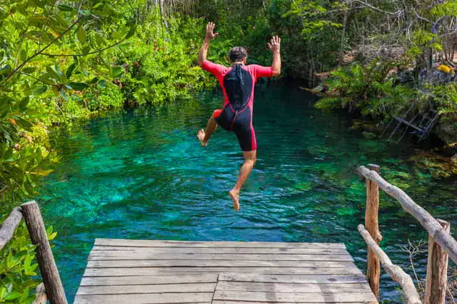 hombre saltando en una zona de clavados en algun cenote de la riviera maya