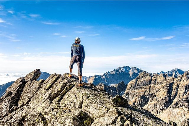 Túrázó férfi a Magas-Tátra egyik sziklás hegycsúcsán, lenyűgöző panorámával