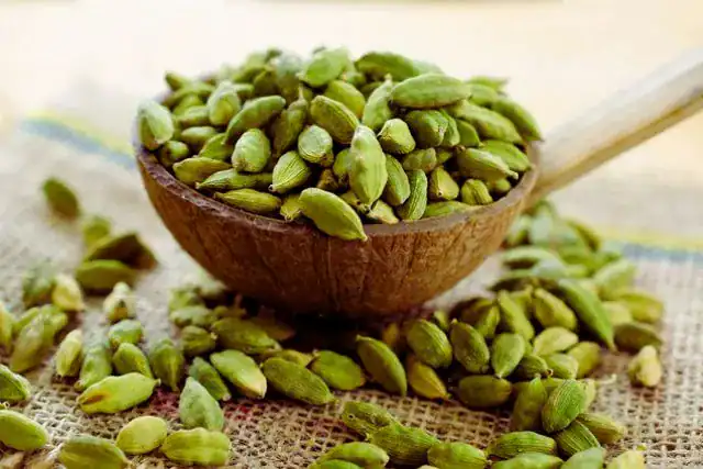 Whole cardamom pods and roasted coffee beans side by side showing natural flavor combination