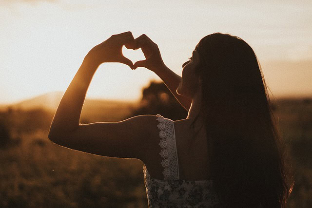 Akzeptanz erlernen in Therapie - Frau formt Herz mit Händen im Sonnenuntergang – Symbol für Selbstakzeptanz und inneren Frieden durch Akzeptanz lernen in der Therapie