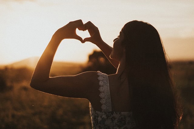 Akzeptanz erlernen in Therapie - Frau formt Herz mit Händen im Sonnenuntergang – Symbol für Selbstakzeptanz und inneren Frieden durch Akzeptanz lernen in der Therapie