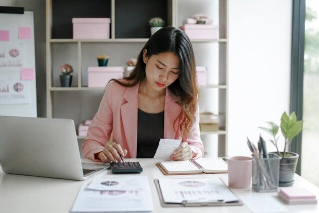 Small-business owner planning a marketing budget with a laptop and calculator.