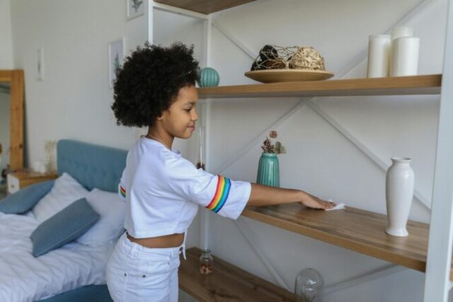Child putting toys away in a labelled bin to help keep their bedroom tidy