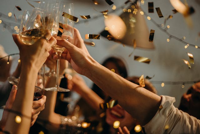 People toasting their wine glasses during a party.