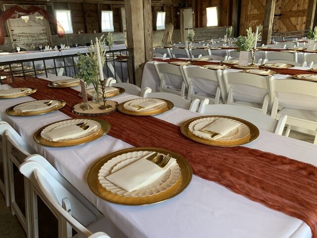 Red and gold place settings inside of barn