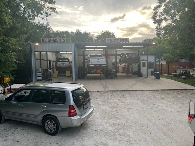 Front of auto mechanic shop, with cars on hydraulic lift 