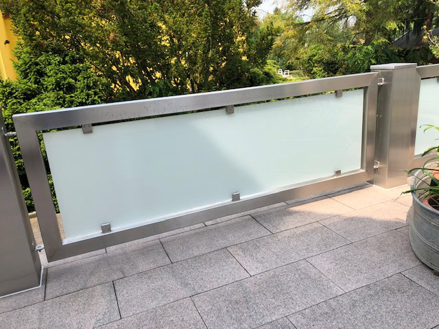 Modernes Terrassengeländer von Stahl- und Metallbau Drost aus gebürstetem Edelstahl mit mattierten Glasfüllungen.