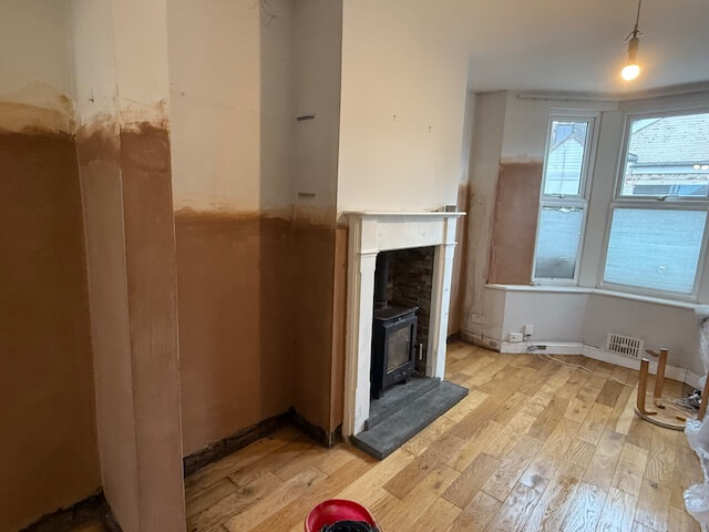 Freshly skimmed plaster drying smoothly around a fireplace and bay window in Bristol