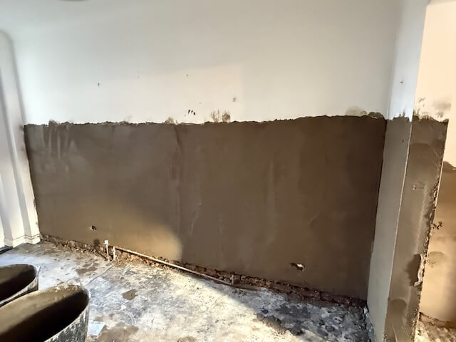 Professional plasterer applying a damp-proof scratch coat to living room walls in Bristol