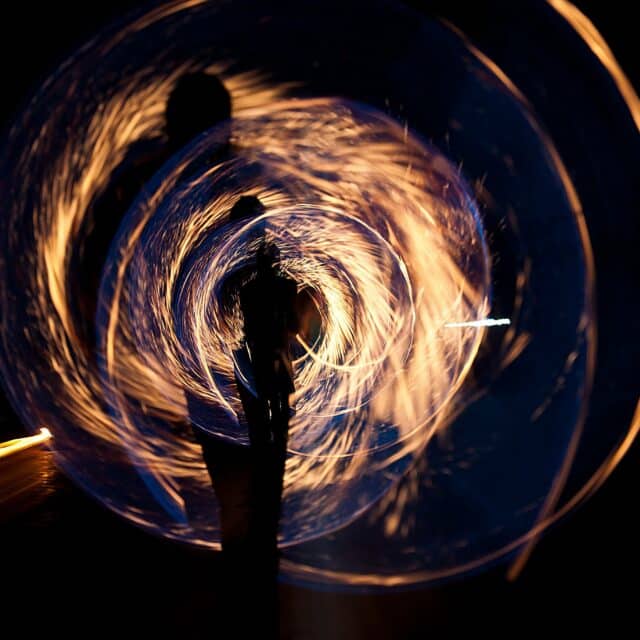 Someone swirls a golden sparkler through the air at long exposure