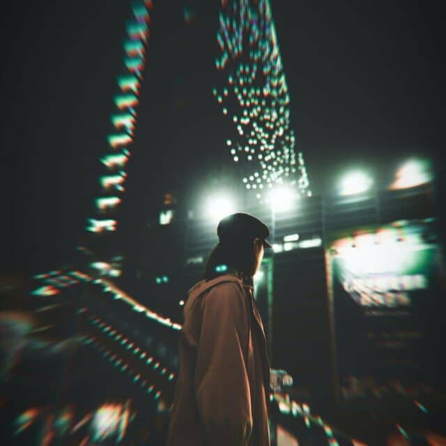 A girl in a cloak stands outside a building at night