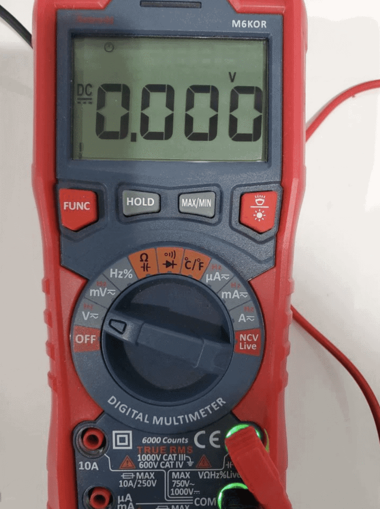 Digital multimeter displaying 0.000 volts in DC mode during an e-bike controller voltage test.