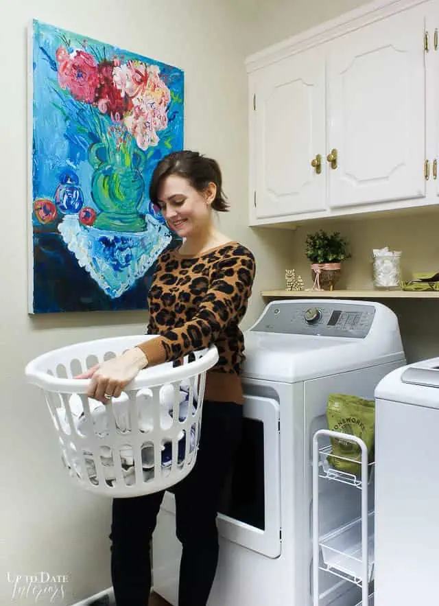 Laundry Room Makeover on a budget before picture with woman holding laundry basket.