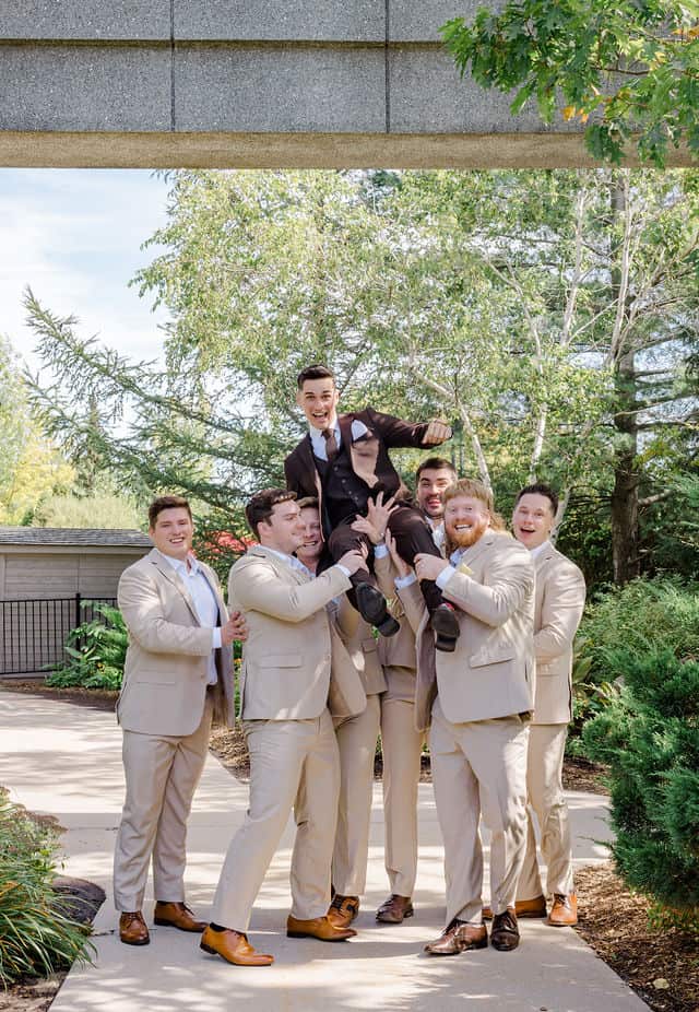 Groomsmen lifting the groom up playfully before the wedding