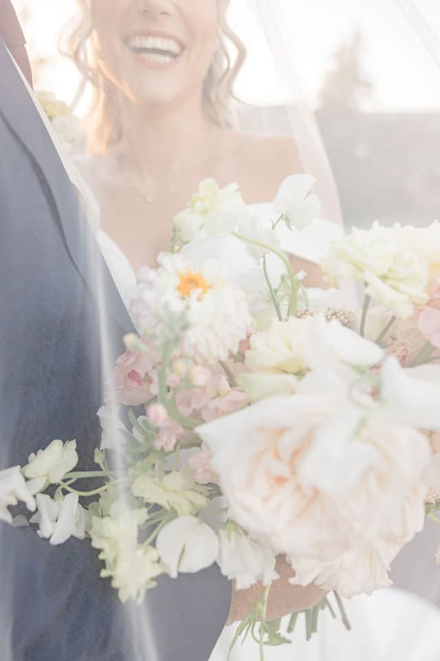 Close up of the bridal bouquet with the bride laughing softly in the background