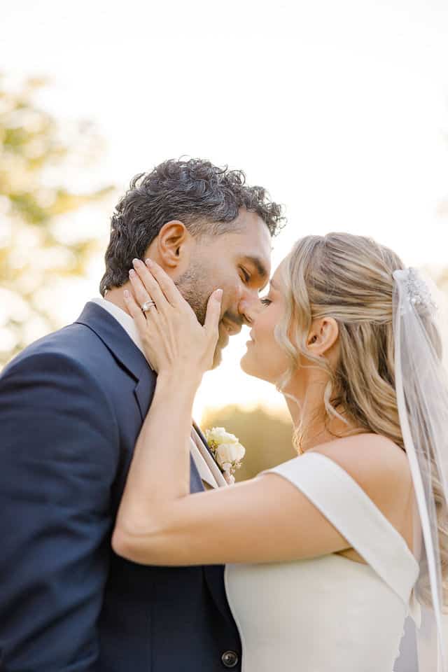 Bride cupping the groom's face for a nose to nose moment at golden hour