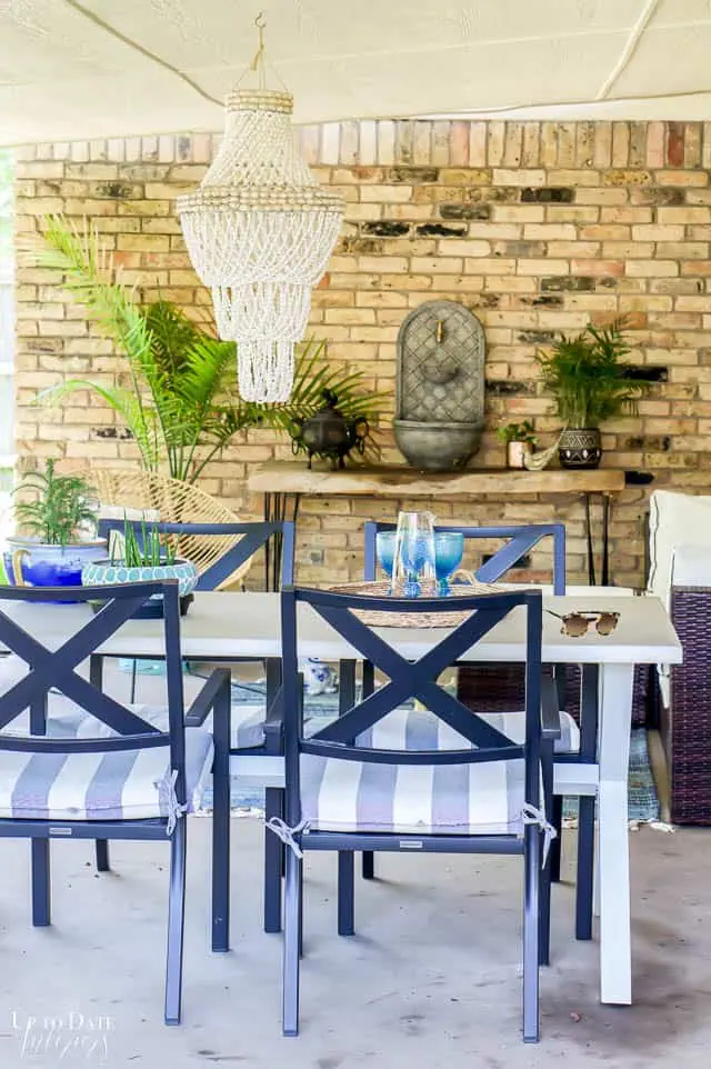 white dining table and wall fountain. Eclectic outdoor living space on back porch.