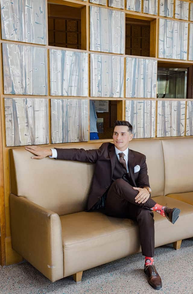 Groom relaxing on a couch in his brown suit before the wedding