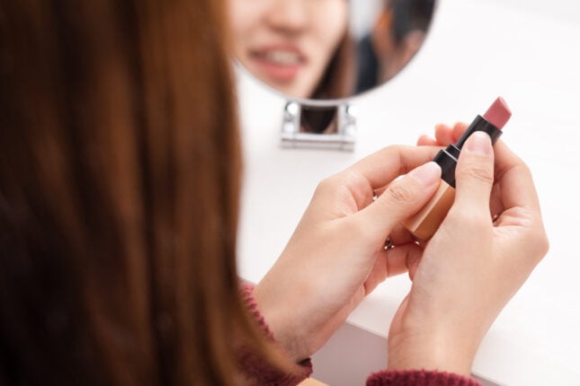 口紅を手にする女性の後ろ姿