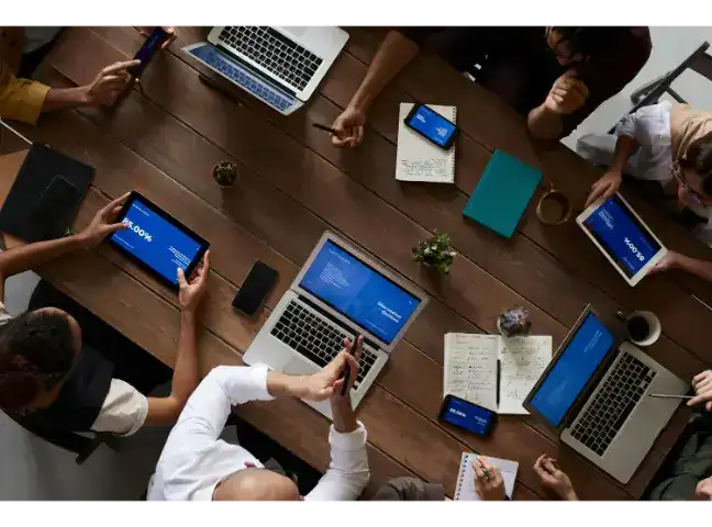 Vedere de sus a unei ședințe B2B cu laptopuri, planificând strategii de automatizare prin Systeme.io.