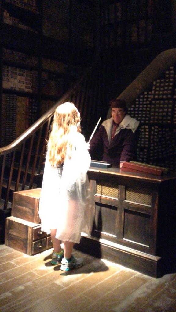 Checkout a young girl interacting with a wizarding staff member at Harry Potter attraction. Perfect for Harry Potter themed vacation destinations.