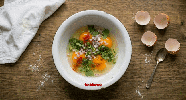 Eggs with chopped onion green chilli coriander and spices in a bowl