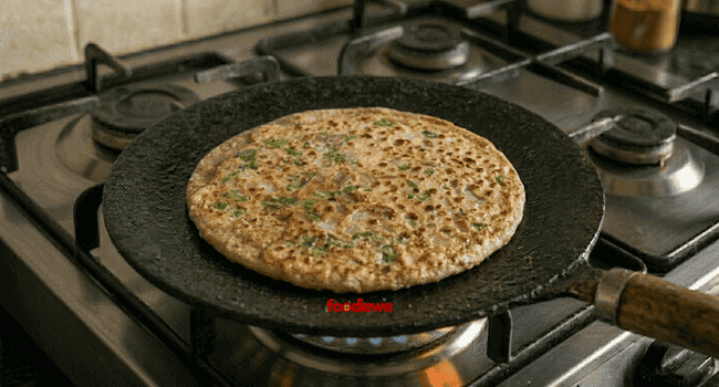 Golden brown egg paratha flipped on tawa showing crispy cooked side