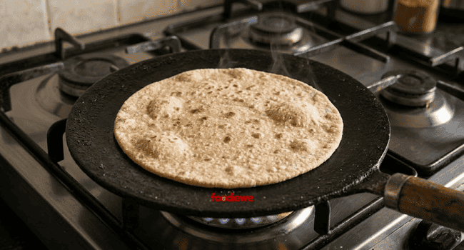 Thin round wheat paratha placed on a hot cast iron tawa