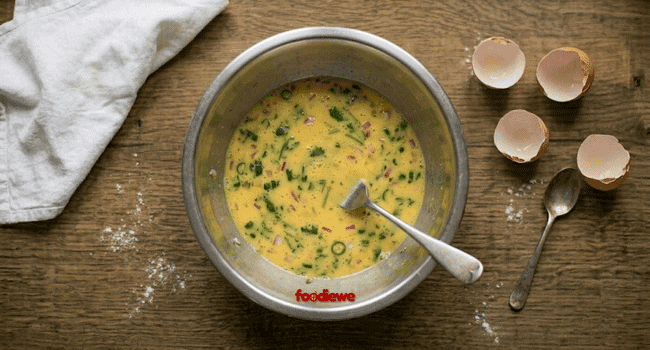 Whisked egg mixture with spices and herbs ready for egg paratha