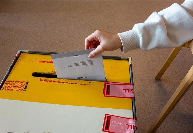 Mano depositando una boleta en una urna, registro de partido ante la JCE