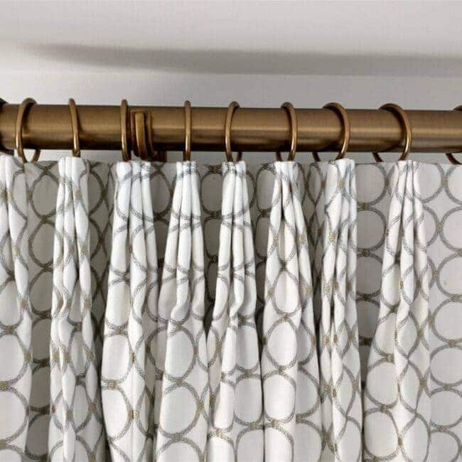 Elegant white curtains with circle design and gold curtain rod.