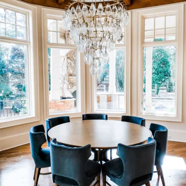 Bright dining space featuring a chandelier, large windows, and contemporary seating.