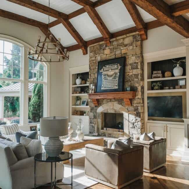 Bright living room with stone fireplace, large windows, and cozy seating area.