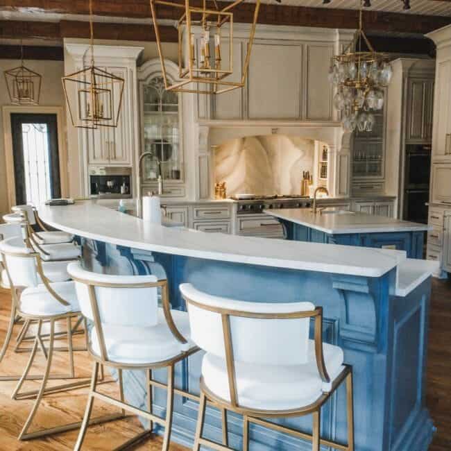 Luxury kitchen island with marble countertop and gold pendant lights.