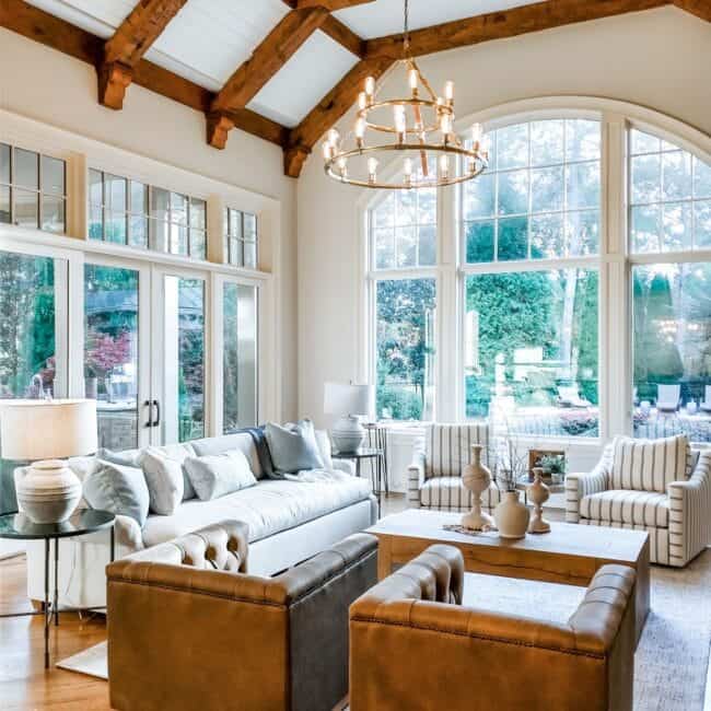 Bright, airy living room featuring high vaulted ceiling and large window backdrop.