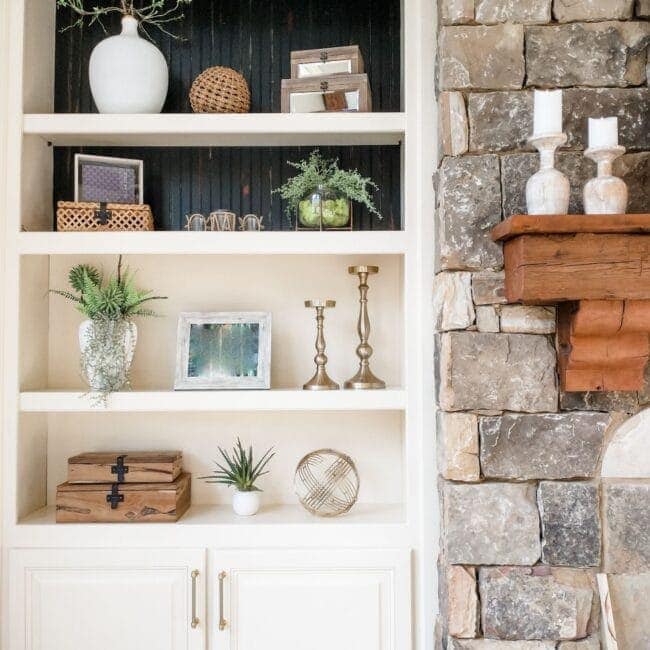 Versatile bookshelf decorated with greenery, candles, mirrors, and storage boxes, perfect for modern living spaces.