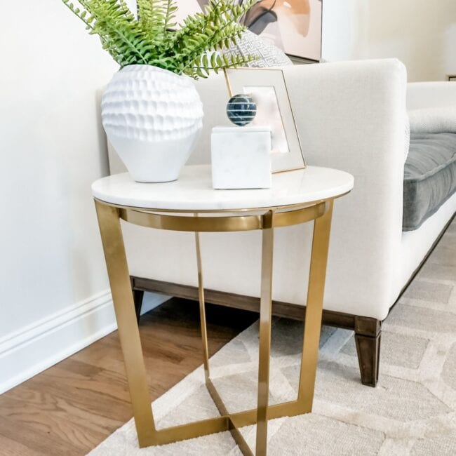 Elegant white and gold accent table with vases, picture frame, and plant decor.