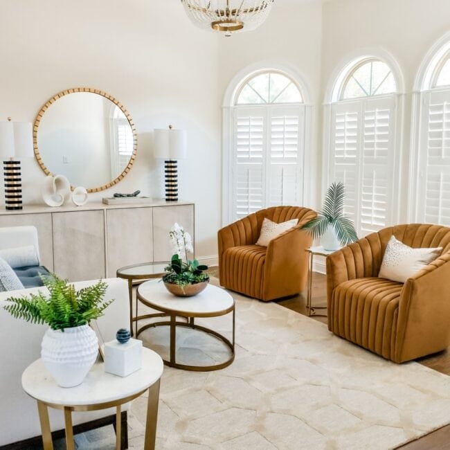 Stylish living space featuring armchairs, monochrome decor, and natural light from arched windows.