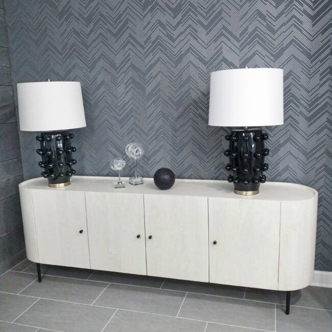 Elegant black and white table lamps on white sideboard with geometric wallpaper, stylish home decoration, modern interior design.