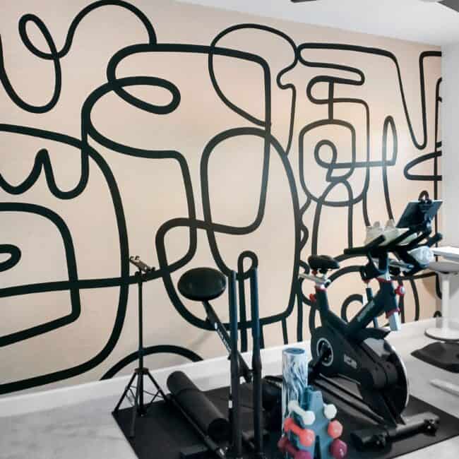 Bright home gym with elliptical trainer, weights, and black wall art for fitness and workout routines.