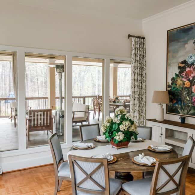 Bright dining area with floral curtains, modern table setting, and a beautiful outdoor balcony.