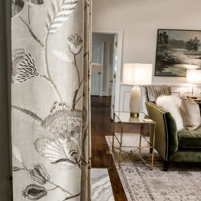 Stunning floral curtain pattern in a modern living room with armchair, rug, and lighting.