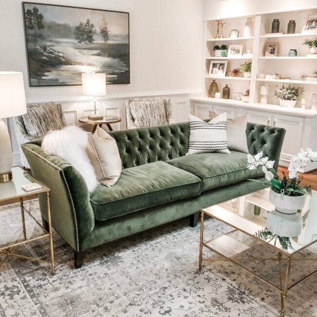 Luxurious green velvet sofa with decorative pillows in a bright living room setting.