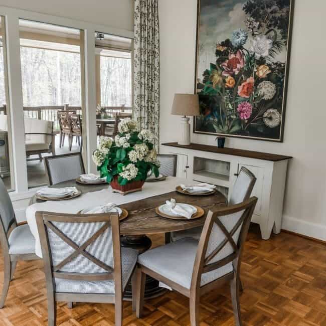 Bright dining space with a large flower painting and elegant table setting.