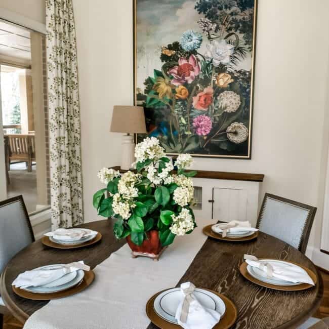 Decorative dining area with white hydrangeas and art wall, modern table setting, cozy ambiance.