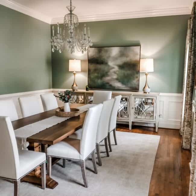 Chandelier, artwork, and white dining chairs in classic room setting.