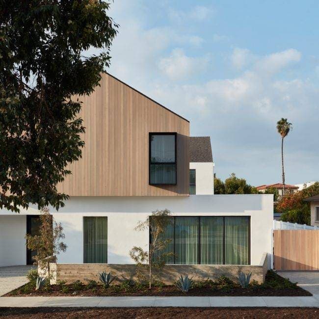 Modern residential house exterior with clean lines, wood accents, and large windows.