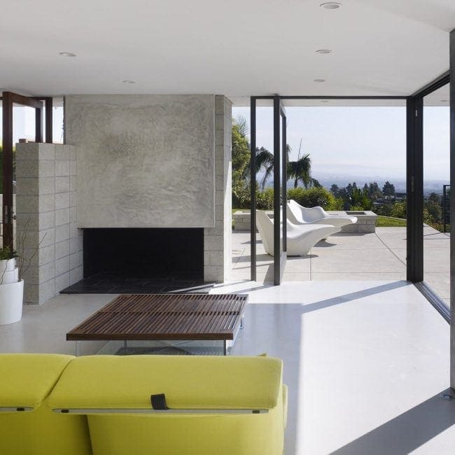 Modern residential living room with floor-to-ceiling glass doors opening to an outdoor pool area.