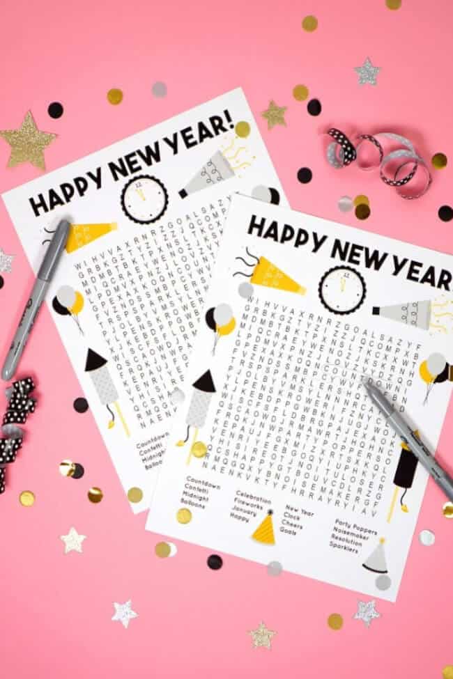 flatlay of word search printable sheets feauting a pink backdrop, confetti and pencils