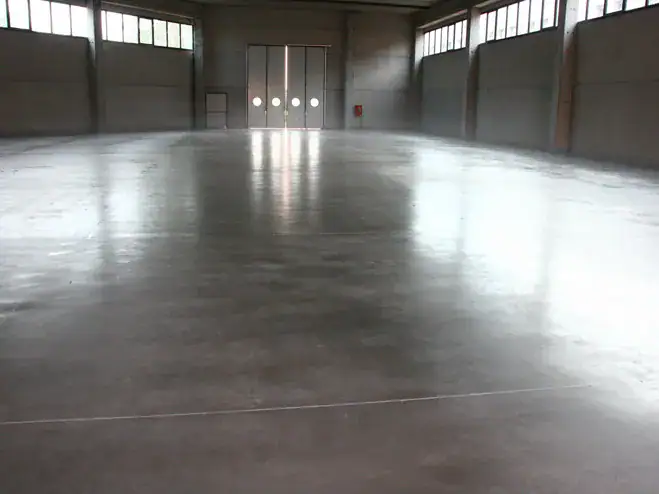 Pavimento industriale in calcestruzzo metodo tradizionale Prima Pavimenti — getto a campi alternati con frattazzatura a elicottero, giunti di contrazione e spolvero al quarzo per capannoni industriali e aree produttive ad alto carico